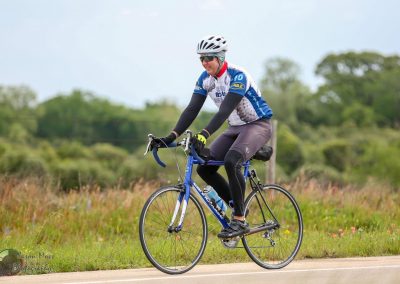 Bright cyclist riding a road bike on scenic outdoor trail during daytime, emphasizing fitness and cycling adventure.