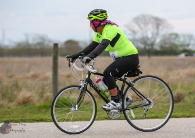 Bright yellow and black cycling jersey with helmet riding bike outdoors during daytime.