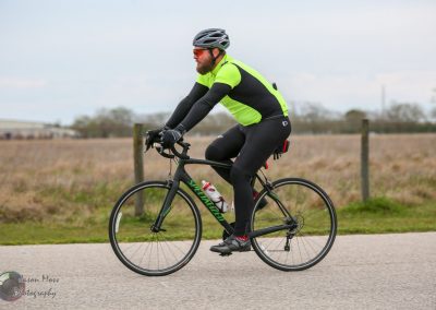 High-performance cyclist on a black Specialized bike during daytime ride, emphasizing outdoor biking and fitness.