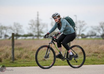 Vibrant woman biking outdoors, promoting Bluebonnet Express cycling adventures and eco-friendly transportation.