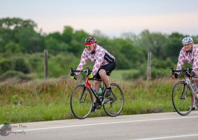 Bright cyclists riding together on a scenic rural road for Bluebonnet Express event.