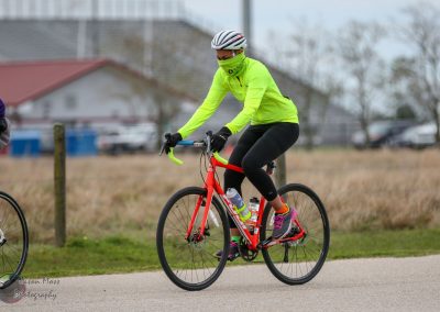Bright yellow cycling jacket and gear on a woman riding a red bike outdoors.