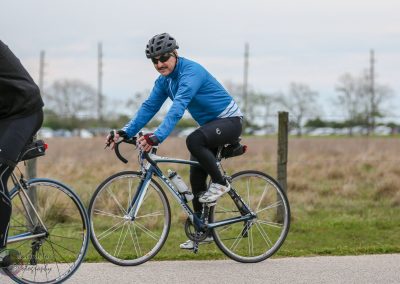 Cyclist in blue jacket riding a road bike during Bluebonnet Express event, outdoor cycling adventure.