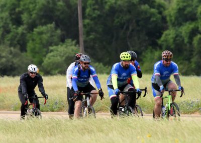 Riders on bicycles participating in Bluebonnet Express cycling event in scenic outdoor setting.