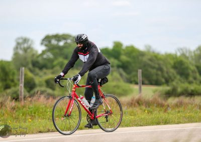 Vibrant red road bike riding through scenic countryside with lush greenery and open skies.