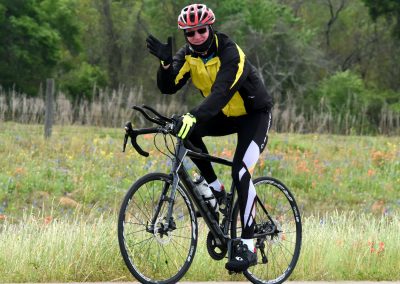 Vibrant cyclist riding mountain bike on scenic trail in lush green landscape.
