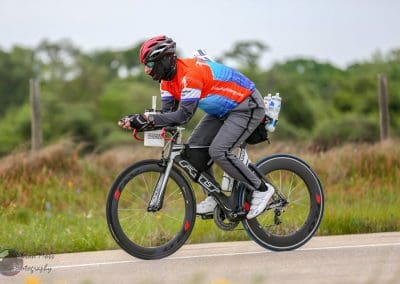 Bright bluebonnet-themed e-bike with aerodynamic design riding on rural road, showcasing eco-friendly transportation.