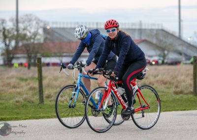 Bright female cyclist riding Bluebonnet Express road bike during outdoor cycling event in fall season.