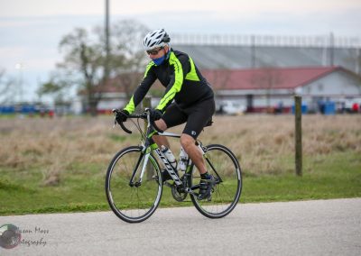 Bright yellow and black cycling jersey with helmet and sunglasses, riding the Bluebonnet Express bike on a scenic outdoor trail.