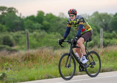 Vibrant cyclist riding a Black Bike on a scenic country trail during daytime.