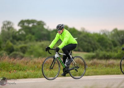 Bright green jacket cyclist riding road bike outdoors for Bluebonnet Express event.