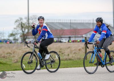 Bright female cyclists enjoying Bluebonnet Express ride, smiling in team jerseys for charity.