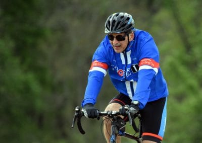 High-performance cyclist wearing a blue uniform riding on a trail during daytime, emphasizing cycling sports and outdoor activities.