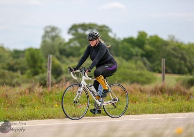 Bright woman cycling outdoors in scenic Texas countryside, promoting Bluebonnet Express bike tours.