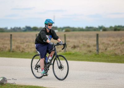 Cyclist riding a Bluebonnet Express electric bike on a rural trail during daytime for eco-friendly transportation.