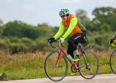 Vibrant cyclist riding a carbon road bike, participating in the Bluebonnet Express event outdoors.