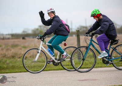 Bright women riding bikes outdoors on a scenic trail, enjoying cycling with helmets and activewear.