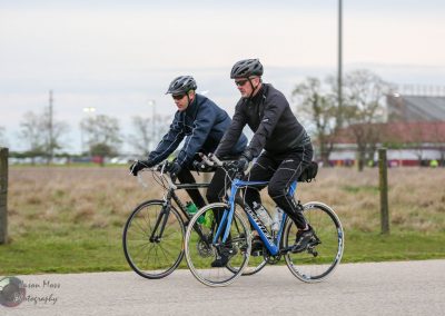 Men cycling on road bikes enjoying outdoor ride with scenic background.
