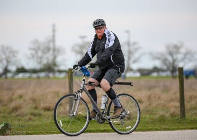 Man riding bicycle outdoors wearing cycling gear, sporty activity, fresh air, fitness, Bluebonnet Express.