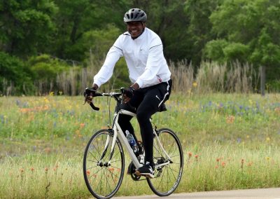 Vibrant cyclist enjoying scenic ride through wildflower meadow on Bluebonnet Express bike trail.