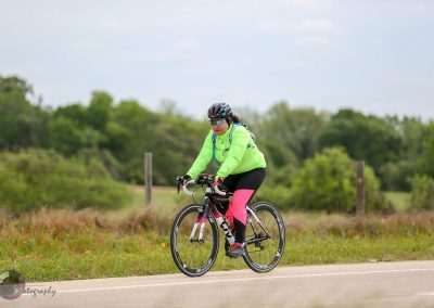 Bright green and pink cyclist riding on scenic outdoor trail, promoting Bluebonnet Express bike services.