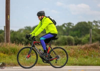 Vibrant cyclist in neon yellow jacket riding on scenic rural trail during daytime.