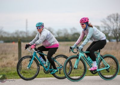 Brightly colored women riding Bianchi bikes on outdoor trail, enjoying cycling in nature.