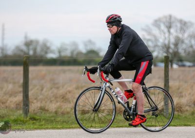 Cyclist riding a road bike outdoors, promoting Bluebonnet Express cycling event.