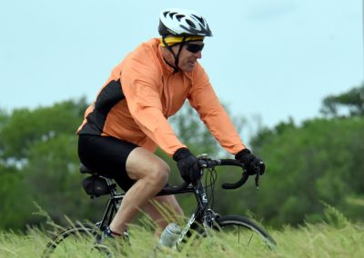 Bright orange cycling jacket, mountain biking on trail, outdoor adventure, healthy lifestyle.