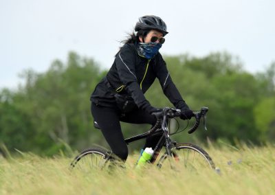 Vibrant cyclist riding a bike through lush green field, outdoor cycling adventure.