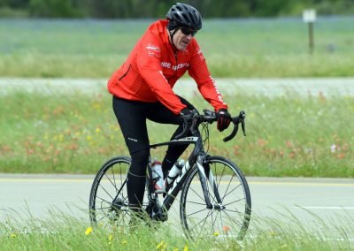 Bright red cycling jacket on rider during outdoor bike ride in lush green field.