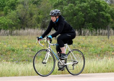 High school girl riding a bicycle on scenic trail for outdoor exercise and fitness.