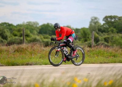 Velo cyclist riding on a scenic rural road during daytime, showcasing Coastal cycling adventure.