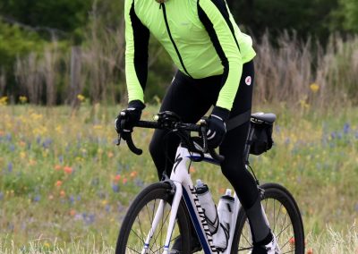 Vibrant cyclist in neon yellow apparel enjoying a scenic ride through spring wildflowers.