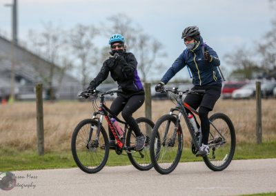 Comfortable women riding electric bikes on outdoor trail for Bluebonnet Express event.