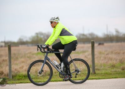Vibrant cyclist in neon yellow jacket on Black Cannondale bike, enjoying outdoor ride on a cloudy day.