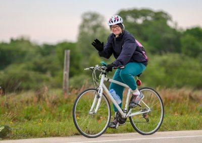 Vivid image of a smiling woman riding a bicycle outdoors, enjoying a scenic ride in nature.