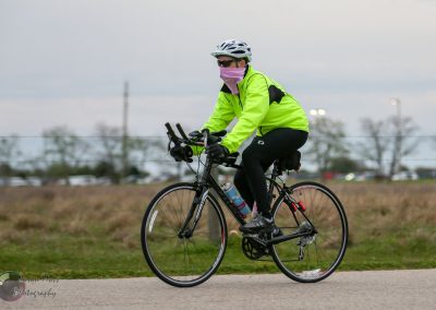 Comfortable cyclist in safety gear riding a bike during daytime on a paved trail.