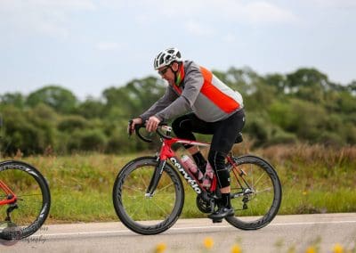 Competitive cyclist riding a Cannondale road bike on open road in natural scenery.