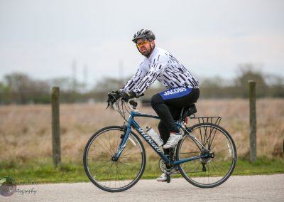 Bright cyclist in stylish white and black cycling jersey riding a Specialized bike on a scenic trail.