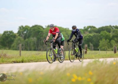 Cyclists riding on a scenic rural road promoting Bluebonnet Express biking events.