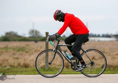 Bike rider wearing red jacket and helmet on a scenic outdoor bike trail.