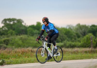 Vibrant cyclist riding an e-bike on scenic rural trail, showcasing Bluebonnet Express bike rides for health and adventure.