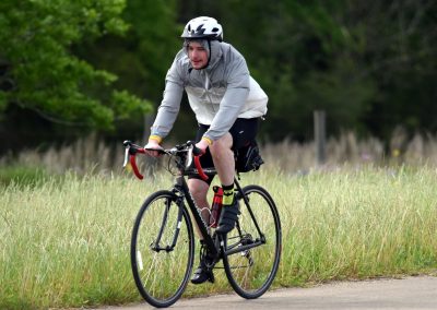 High-performance road bicycle riding near nature, cyclist in rain gear on a scenic trail.
