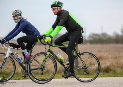 Vibrant green and black road bikes riding outdoors on a cloudy day.