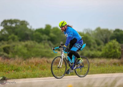 Vibrant cyclist on Bluebonnet Express bike route with scenic greenery background.