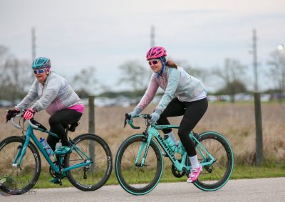 Vibrant women cycling their blue bikes outdoors, enjoying a healthy ride on a cloudy day.