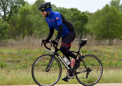 Smooth road cycling with Bluebonnet Express on a scenic outdoor trail, featuring a rider in professional gear.