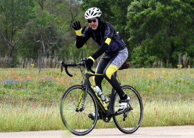 Vibrant cyclist riding a black and yellow bike through a scenic wildflower field.