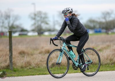 Vegan woman cycling outdoors on Bluebonnet Express bike trail with scenic countryside views.